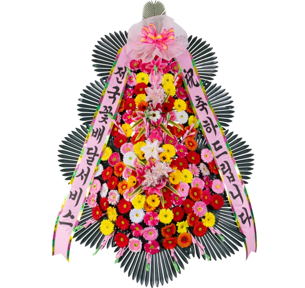 Three-tier deluxe standing congratulatory wreath densely packed with red, pink, yellow, orange and white gerberas and pink oriental lilies, pink sashes, on a white background