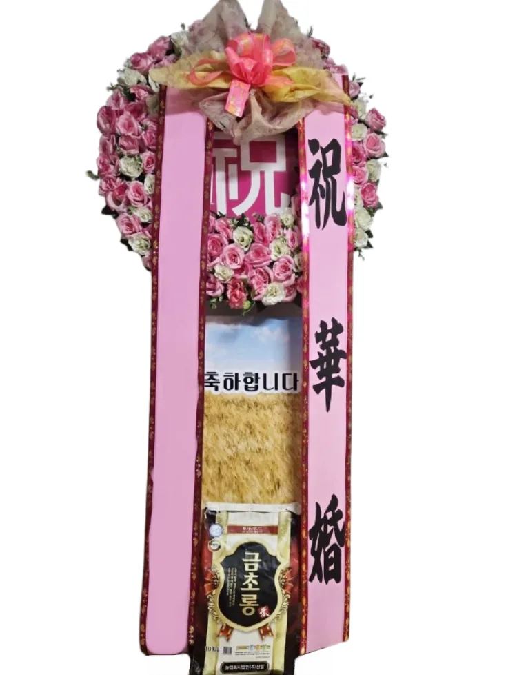 Standing congratulatory wreath of pink roses with two sashes and a 10 kg bag of rice at the base
