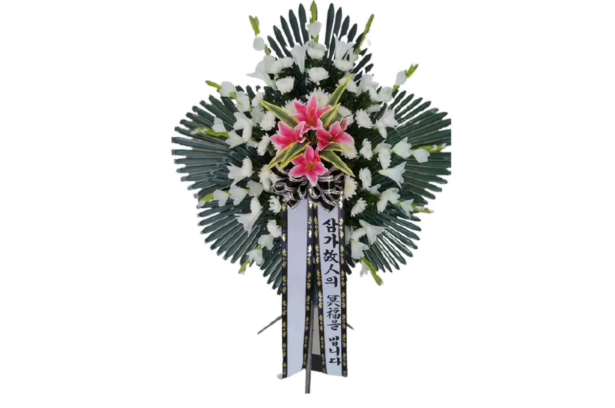 Standing sympathy arrangement with pink lilies, white gladiolus and white chrysanthemums on a fan of dark foliage, with a condolence sash — Geochang version