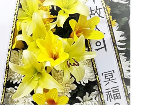 Close-up of yellow lilies and white chrysanthemums beside a sash