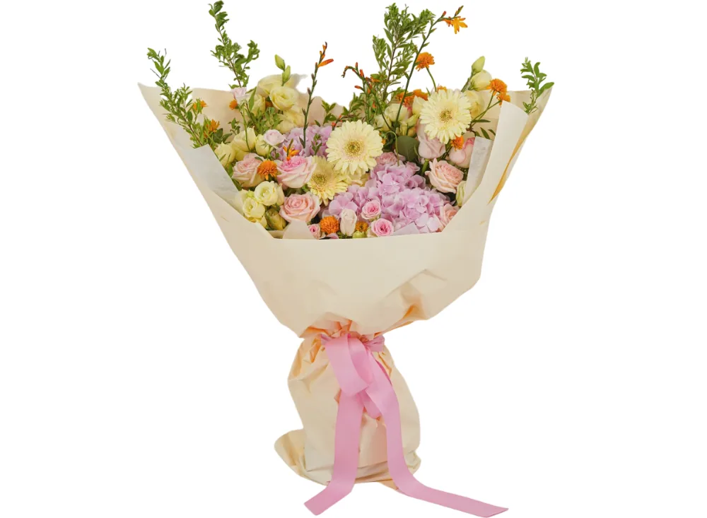 Bouquet of yellow gerberas, pink roses, pink hydrangea, pale yellow lisianthus and orange accent blooms in a cream wrap with a pink ribbon
