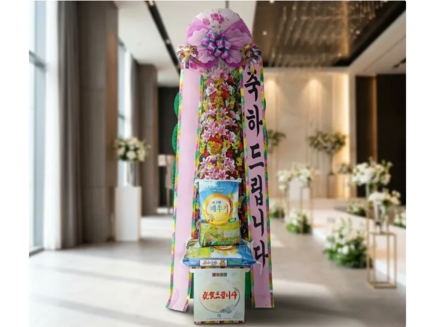 Standing rice wreath with a pink sash and two 10 kg rice bags on the stand, in a wedding hall