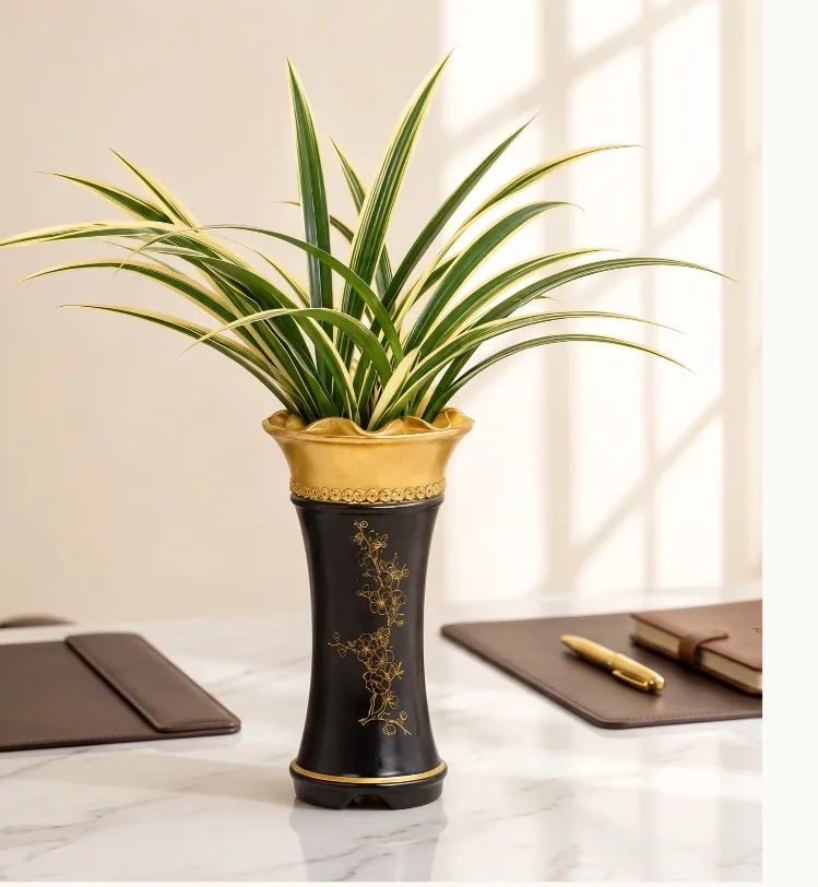 Oriental orchid with gold-edged leaves in a black ceramic pot with a gold rim, on a marble desk